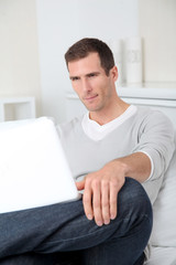 Closeup of adult man sitting on sofa with laptop computer