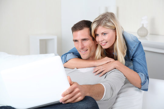 Closeup of couple sitting in sofa surfing on internet
