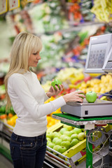 Beautiful young woman shopping for fruits and vegetables in prod