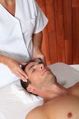 Fototapeta na wymiar Man having a facial massage in spa center