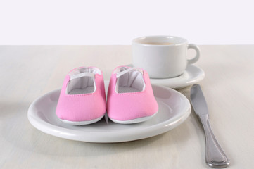 pregnancy concept baby shoes on the breakfeast table