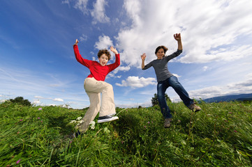 Fototapeta na wymiar Mother and son jumping, running against blue sky