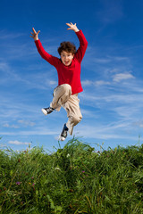 Boy jumping, running against blue sky