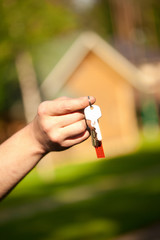 hand holding keys, house in the background