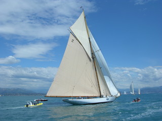 Fototapeta na wymiar Classic wood yacht in regatta with white sails blue sky and sea