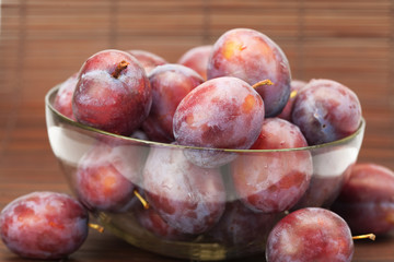 plums in a glass bowl on a bamboo mat