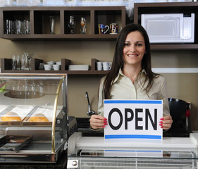 Happy owner of a café showing open sign