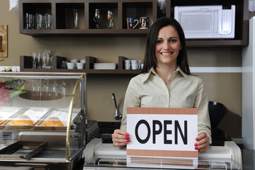 Happy owner of a café showing open sign
