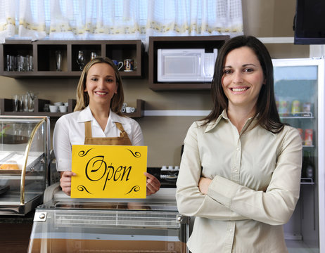 Happy owner of a café showing open sign