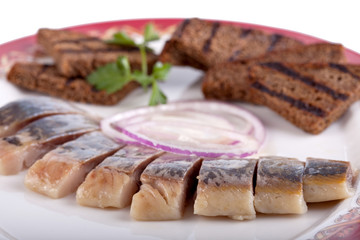herring with crackers on a plate. object on a white background