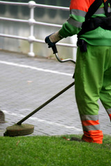 Jardinero cortando el césped en un parque público