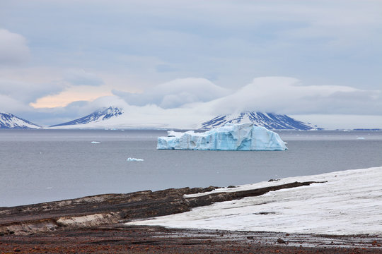 Arctic landscape with icebergs and stormy winter sky