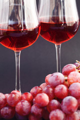 glass of wine and a bunch of grapes on a black background