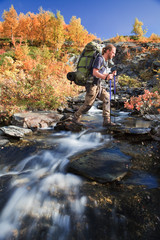 Wanderer beim Queren eines Baches im Herbst