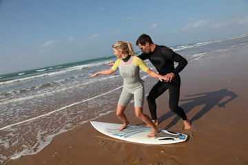 Man teaching young woman to surf