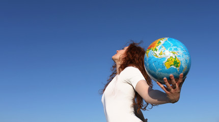 woman holding a globe under blue sky