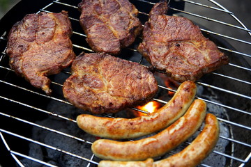Grill mit Grillfleisch und Bratwurst im Garten
