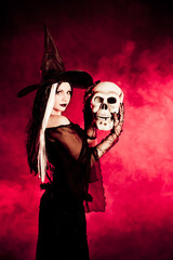 Halloween witch with a skull over black background