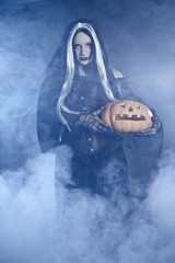 Portrait Halloween witch with a pumpkin