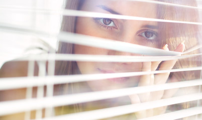 Attractive girl looks out blinds