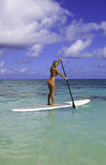 teenage girl in bikini on a paddle board in hawaii