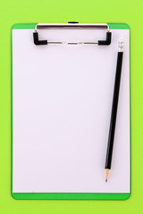 Clipboard and pencil on green background