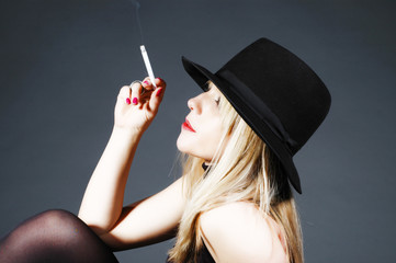 Beautiful blonde girl smoking, portrait in a studio
