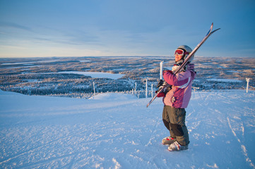 Little girl-skier on the hill watching the sunrise at a ski reso