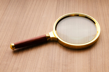Magnifying glass with wooden handle on the flat surface