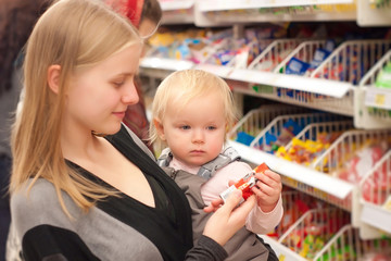 Obraz premium young mother and toddler girl shopping cookies in supermarket