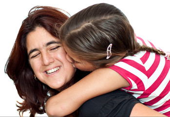 Small girl kissing her young latin mother on a white background