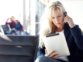 Business women calling and working at the Airport with touchpad