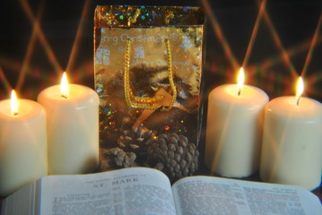 Student studying Bible at christmas by candlelight