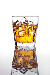 Glass of scotch whiskey and ice on glass table