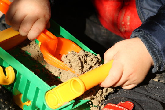 Kind bel&auml;dt einen Spielzeuglaster mit Sand