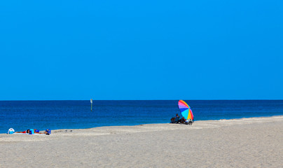 Fototapeta na wymiar Colorful Beach Umbrella on a sandy beach with blue sky and ocean