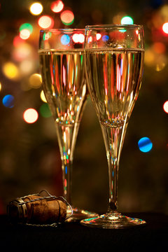 Two champagne glasses, a cork and defocused christmas tree