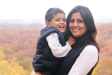 Smiling mother holding son outdoors in the fall
