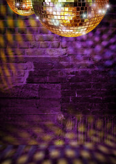 Golden mirror balls reflect lights on purple disco brick wall