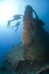 Scuba divers exploring the propellor area of a shipwreck.