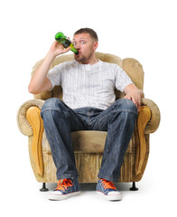 Man sits in an armchair and drinks beer on withe background