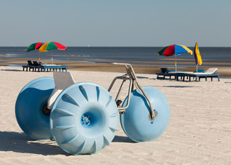 Beach tricycle and lounge chairs & umbrellas along the shoreline