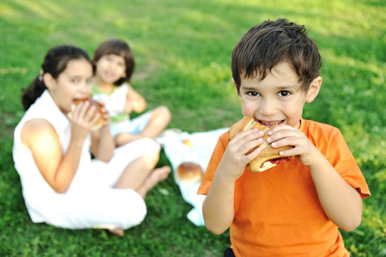 Small Group Of Children In Nature Eating Together, Sandwiches