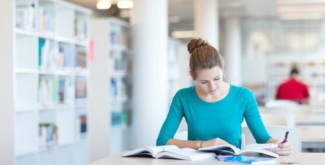 Fototapeta premium pretty young college student in a library (shallow DOF; color to