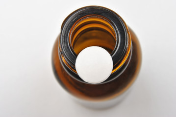 one white pill and a brown bottle