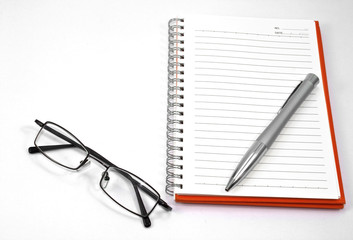 orange notebook and eyeglasses