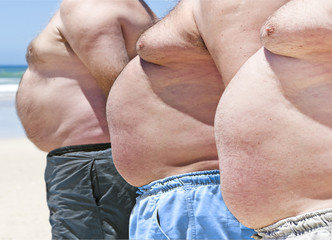 Close up of three obesely fat men on the beach