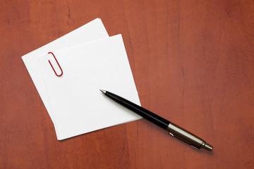 White paper note with a clip and pen