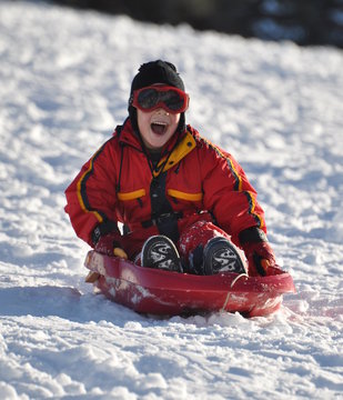 enfant gar&ccedil;on joyeux qui descend avec sa luge