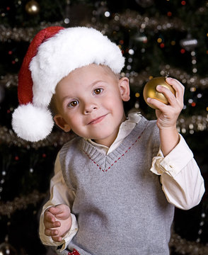 Adorable little boy in a Santa Hat holding an ornament
